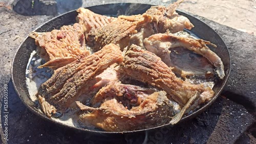 Fish is fried in frying pan close up. Cooking fresh fish catch. Successful fishing. Delicious fish dish fried over fire. Dish from fried fish cooked on fire. Pleasant rest Frying pieces of fish