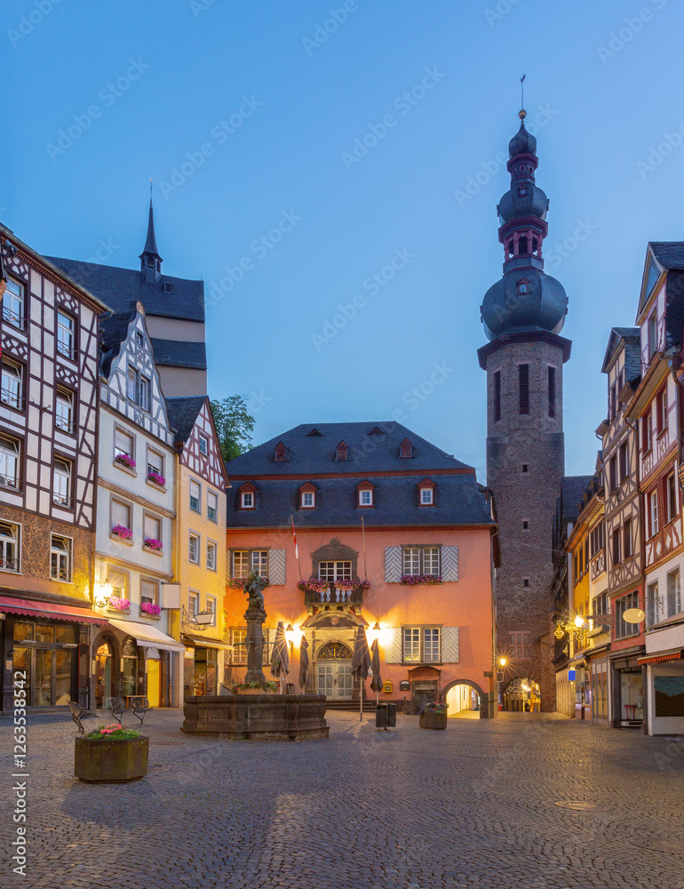 Naklejka premium Evening view of the historic Market Square in Cochem, Germany, with half-timbered houses, town hall and tower of St. Martin's Church