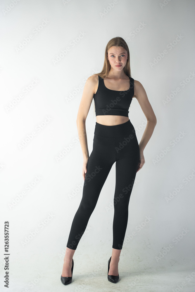 professional model in a sleek black outfit adjusts her jeans while gazing off-camera, showcasing her well-defined features and graceful body language professional model in a sleek black outfit adjusts her jeans while gazing off-camera, showcasing her well-defined features and graceful body language