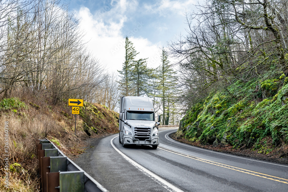 White high cab big rig semi truck transporting cargo in refrigerator semi trailer driving on the winding road in Columbia Gorge White high cab big rig semi truck transporting cargo in refrigerator semi trailer driving on the winding road in Columbia Gorge