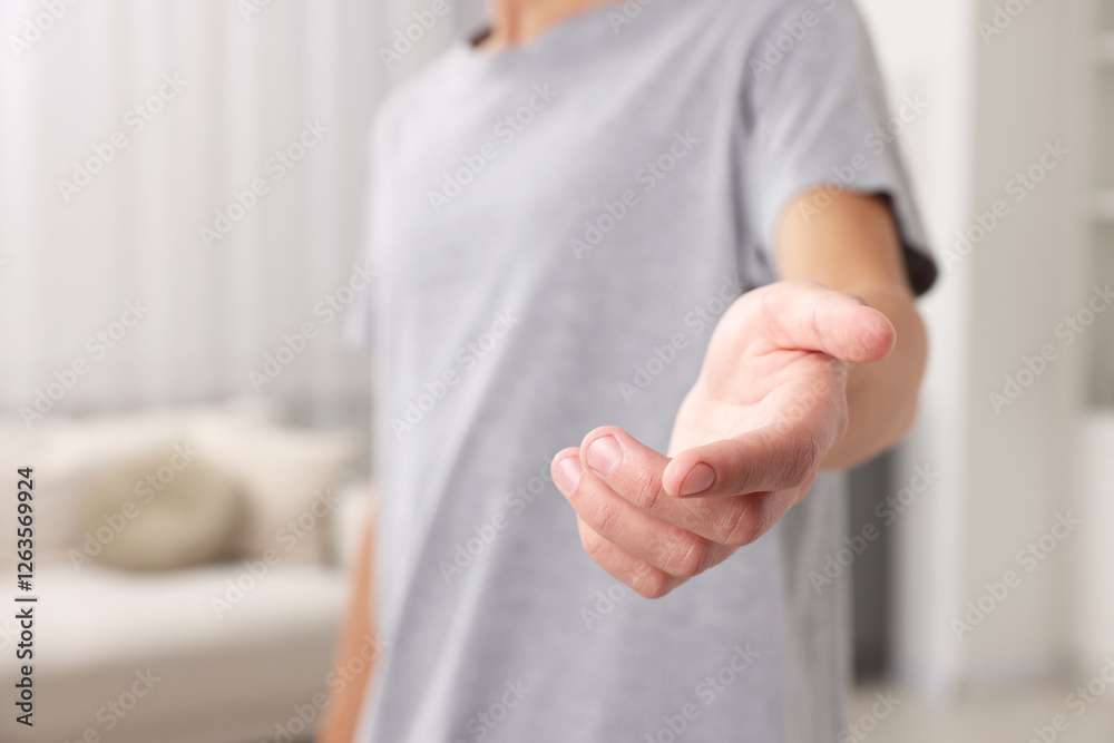 Fototapeta premium Offering help. Man reaching his hand indoors, closeup