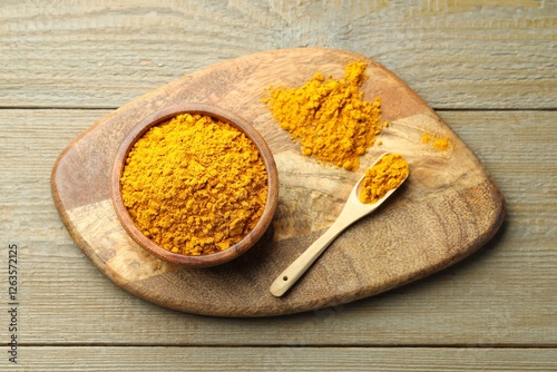 Fototapeta Naklejka Na Ścianę i Meble -  Turmeric powder in bowl and spoon on wooden table, top view
