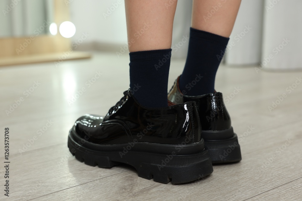 Little girl wearing oversized shoes indoors, closeup