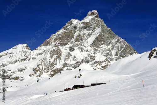 Obraz na płótnie Snowy terrains below the Matterhorn peak - Monte Cervino, Italy. The mountain lies on the border between Switzerland and Italy, above the Swiss town of Zermatt and the Italian town of Breuil-Cervinia w salonie