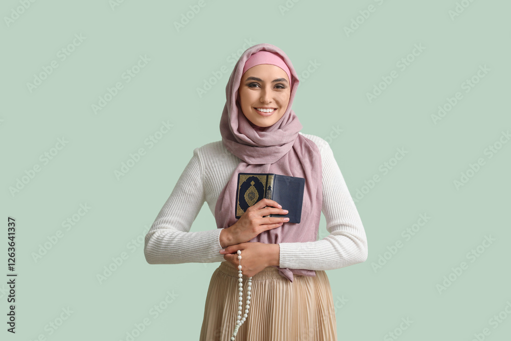 Fototapeta premium Young Muslim woman with Koran and prayer beads on green background. Islamic New Year celebration