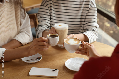 Canvastavla Women with cups of delicious coffee drinks at wooden table in cafe, closeup