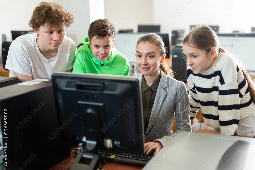 Female teacher helping schoolboy and schoolgirl in computer class Female teacher helping schoolboy and schoolgirl in computer class