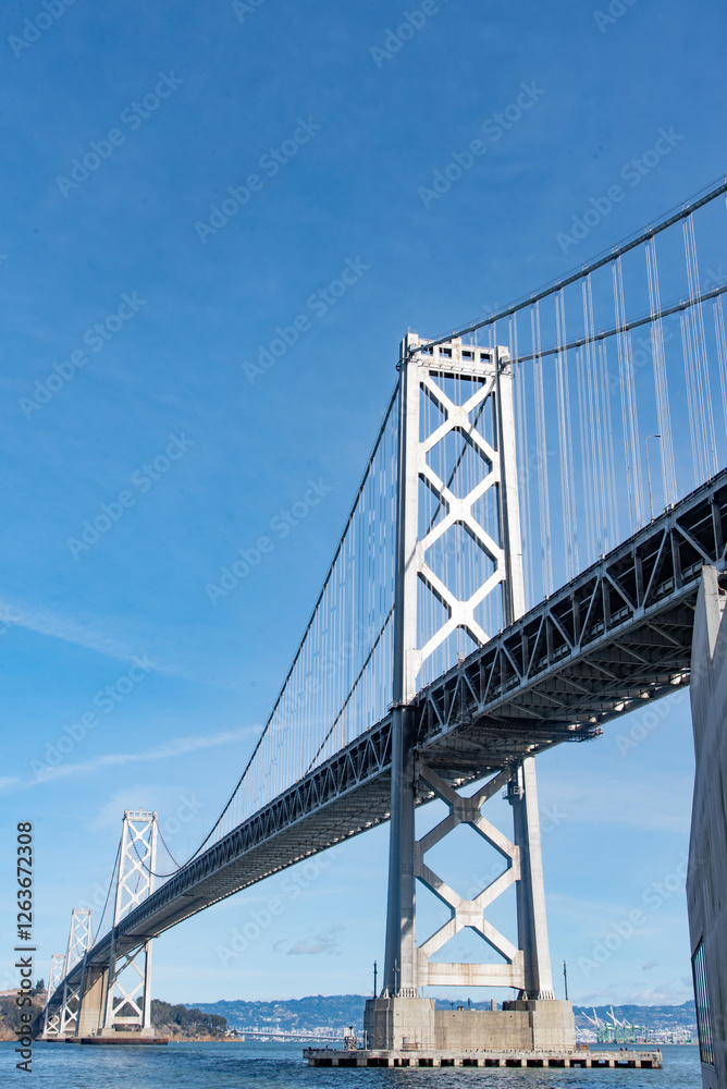 A large bridge spans a body of water, with a clear blue sky above A large bridge spans a body of water, with a clear blue sky above