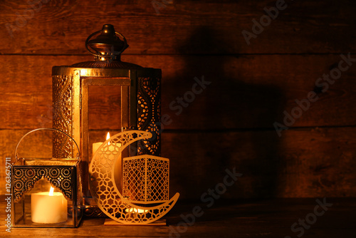 Muslim lamps with burning candles and decorative crescent for Ramadan on wooden background photo