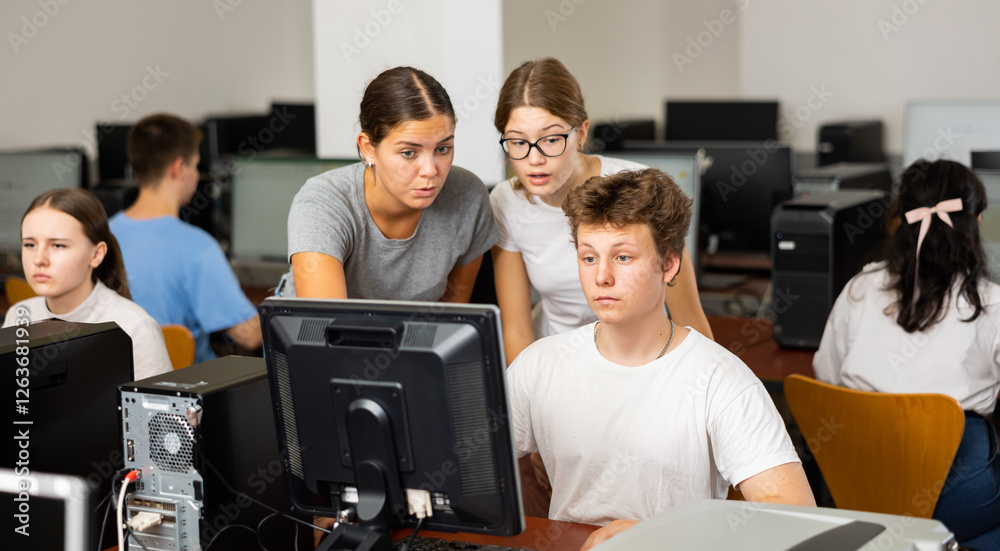 Fototapeta premium Young female teacher working with students in computer class of university
