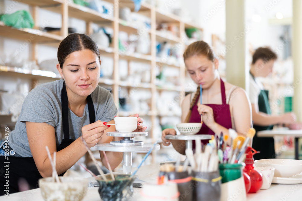 Teenagers are interested in making dishes from clay in a pottery workshop Teenagers are interested in making dishes from clay in a pottery workshop