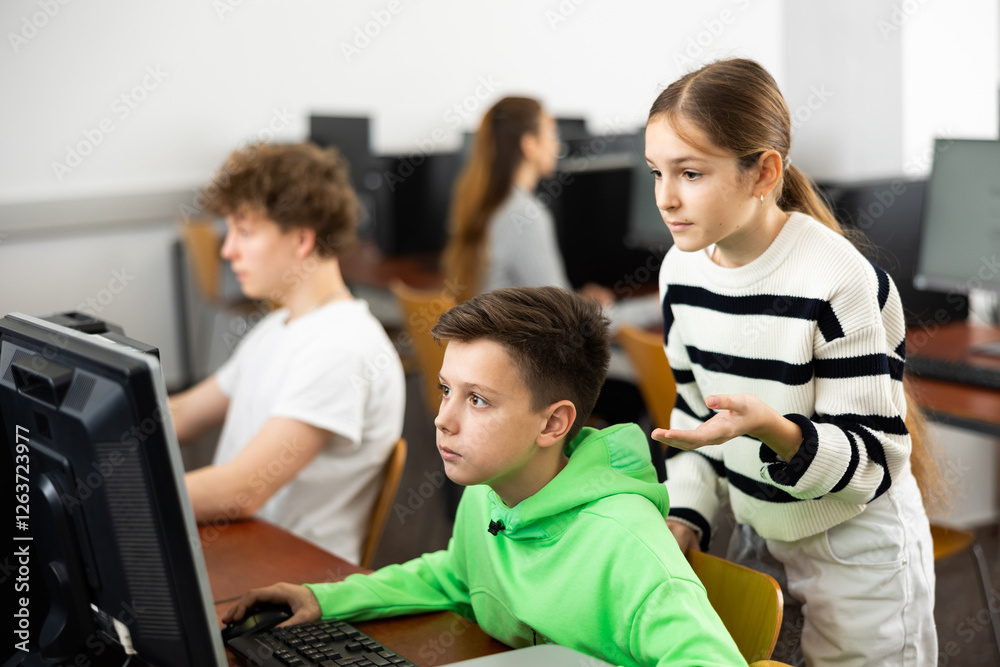 Teenager boy using computer in classroom to help his classmate, young girl, to solve problem. Teenager boy using computer in classroom to help his classmate, young girl, to solve problem.