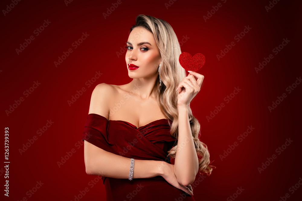 Attractive woman in red dress holding a heart shape symbol on a burgundy background Attractive woman in red dress holding a heart shape symbol on a burgundy background