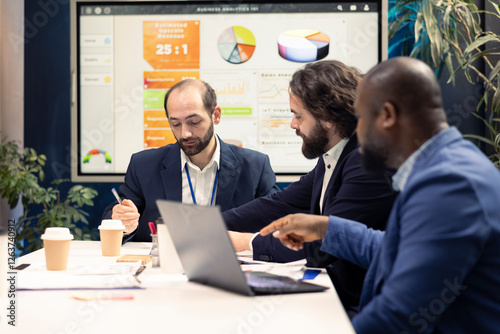 Startup employees exchanging project details and essential information about achieving business goals, establishing budget and other resources. Management team sharing information in a meeting. photo