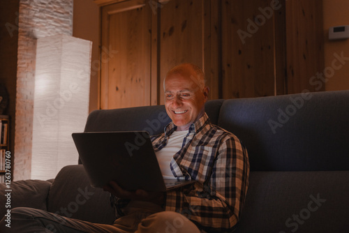 Man on the couch with laptop - online concept of distance study work.