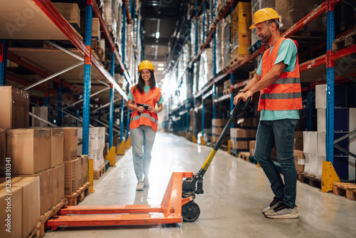 Warehouse workers managing inventory and logistics with hand pallet truck and scanner