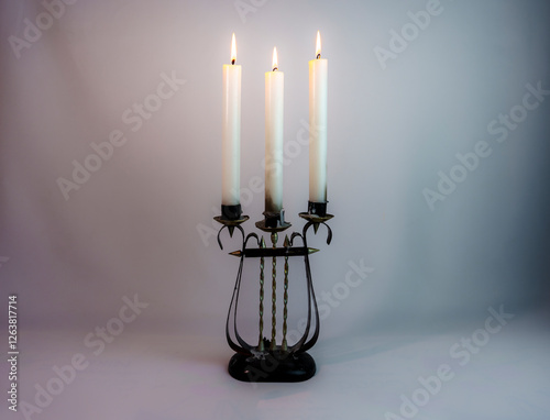 Vintage candelabrum with three burning candles on a neutral background photo