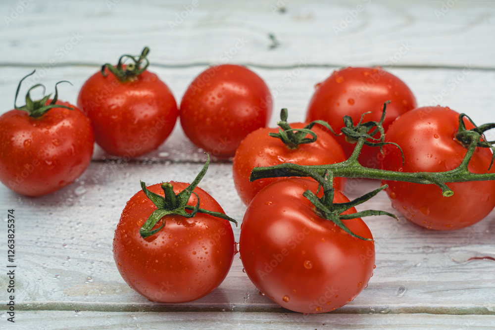 Fresh red tomatoes on the vine with water droplets on rustic wooden background Fresh red tomatoes on the vine with water droplets on rustic wooden background