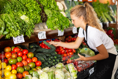 Obraz na plátně Focused fifteen-year-old girl who works part-time in a store as a trainee salesw