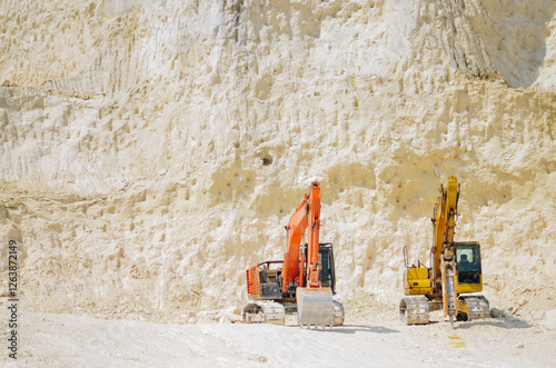 Excavator on limestone mountain. Backhoe digging sand, soil on limestone mountain, Heavy construction equipment is digging at construction site. Excavator is working on soil, foundation. Road construc