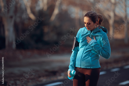 Tired Jogger Feeling a Pain in her Chest Taking a Break. Running woman feeling sick after intense physical activity 
