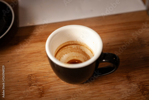 A nearly finished espresso reveals its telltale residue on the ceramic cup, highlighting coffee culture’s daily ritual of quick, robust shots and friendly cafés. photo