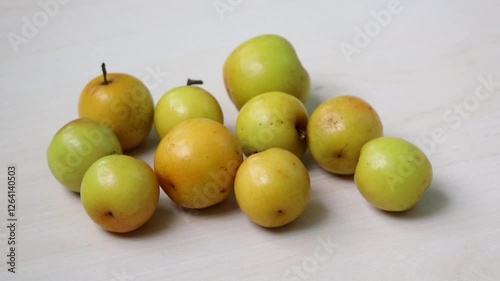 Fresh plum fruits rest on a light wooden surface. These are called Boroi or Kul in Bangladesh and are also known as Indian jujube, Chinese date, or Chinee apple. photo