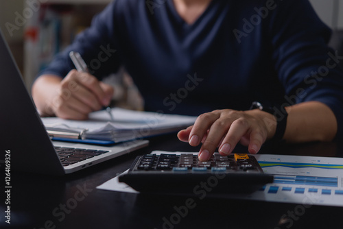 Businessman using a calculator and writing financial data. Budget planning, accounting, tax calculation, expense tracking, and financial management for corporate and personal finance.