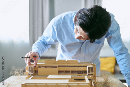 事務所で建築の模型を見て建物を想像して設計する建設業の30代の男性 photo