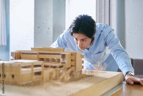 建築模型を見て建物の条件や予算を分析しプランニングをする1人の男性
