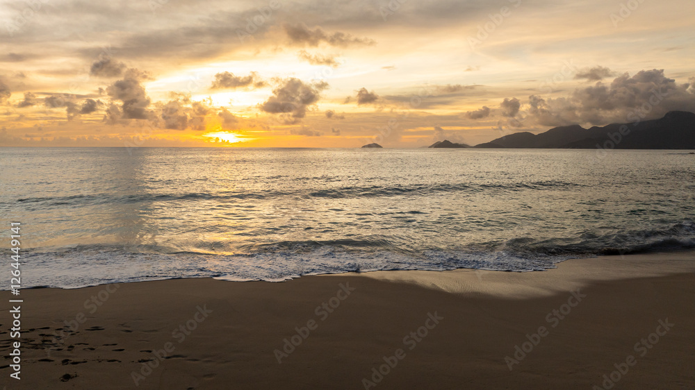 Sunset over calm ocean waves with gentle reflections on the wet sandy shore. Seychelles, Mahe. Sunset over calm ocean waves with gentle reflections on the wet sandy shore. Seychelles, Mahe.
