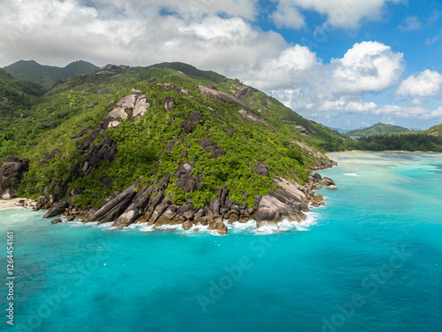 Crystal clear ocean meets rugged cliffs covered in greenery. Seychelles, Mahe.