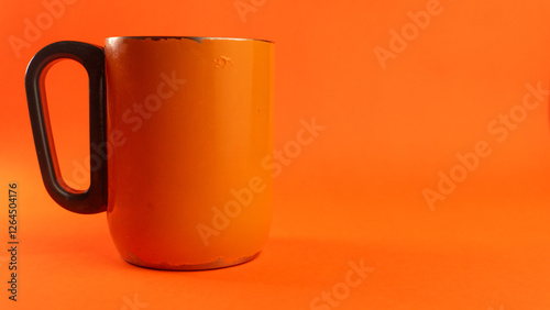 an orange cup whose paint has started to peel off, isolated in orange