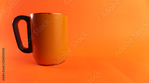 an orange cup whose paint has started to peel off, isolated in orange