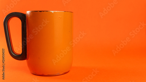 an orange cup whose paint has started to peel off, isolated in orange
