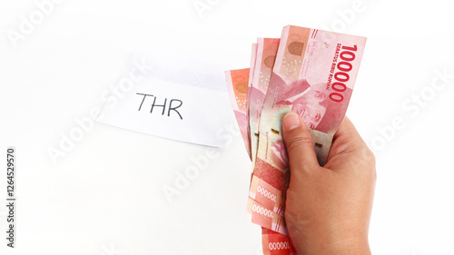 Indonesian Money, rupiah or IDR in envelope with THR Text. Hand holding THR envelope. THR is holiday allowance on Eid al-Fitr or Lebaran days. background white best quality. photo