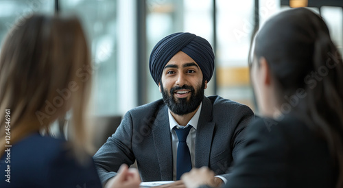 A man in a suit and turban engages in a discussion with two women in a professional setting. photo