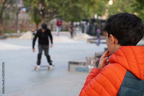 child watching with interest the skaters at a kate park before learning to skate himself