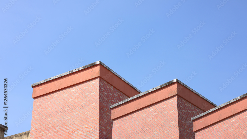 Red brick apartment building with sky, Shapes and simplicity of architecture, Fragment of roof of modern private dwelling house against of sky, Blue sky and Sunlight in background with copy space. Red brick apartment building with sky, Shapes and simplicity of architecture, Fragment of roof of modern private dwelling house against of sky, Blue sky and Sunlight in background with copy space.