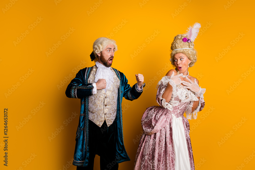 Fototapeta premium Joyful couple in vintage costumes portraying royalty against a vibrant yellow backdrop, showcasing historic charm and cosplay creativity