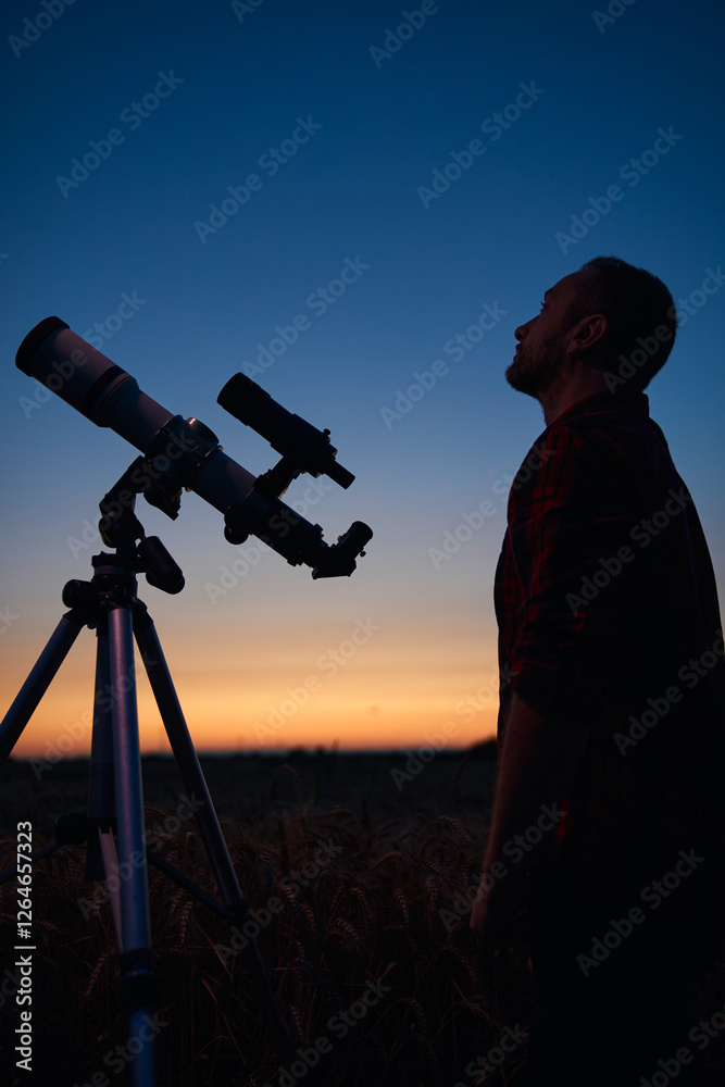 Astronomer looking at night sky with a telescope.