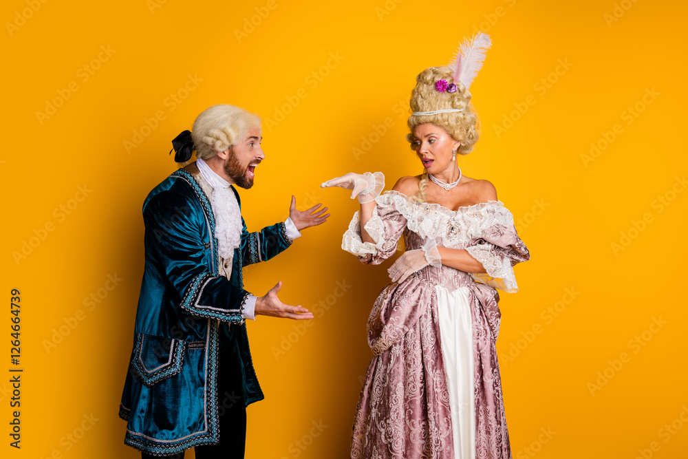 Fototapeta premium Elegant couple in historical costumes posing playfully against a vibrant yellow backdrop