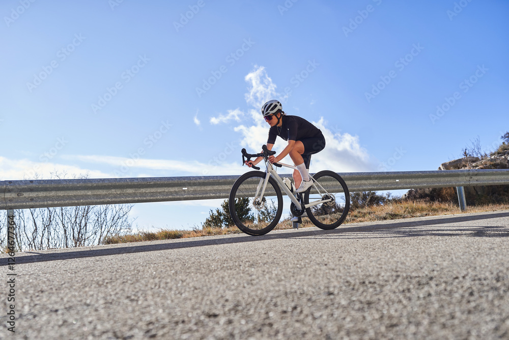 Fototapeta premium Female cyclist descending a mountain road on a road bike
