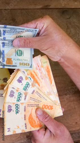 Vertical image of Two pairs of hands exchanging many 1000  peso bills  for two 100 American dollar bills, signifying the exchange rate, dollar blue and hyperinflation economic situation photo