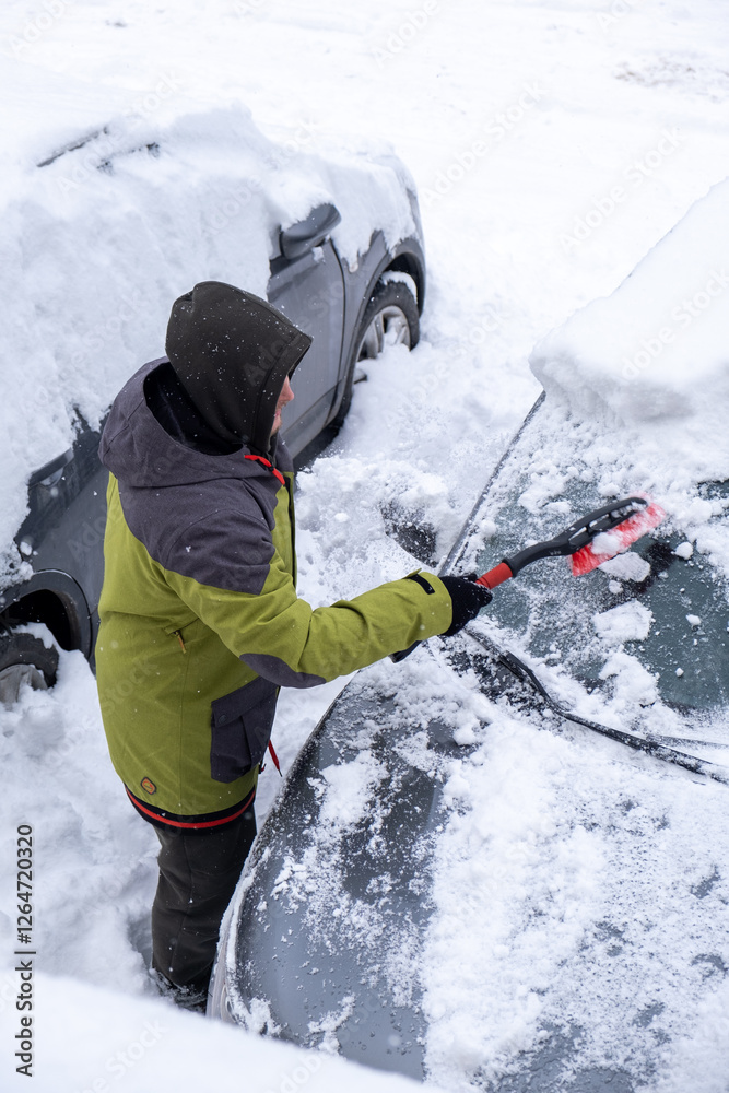 Person Clearing Snow from Car in Winter Landscape