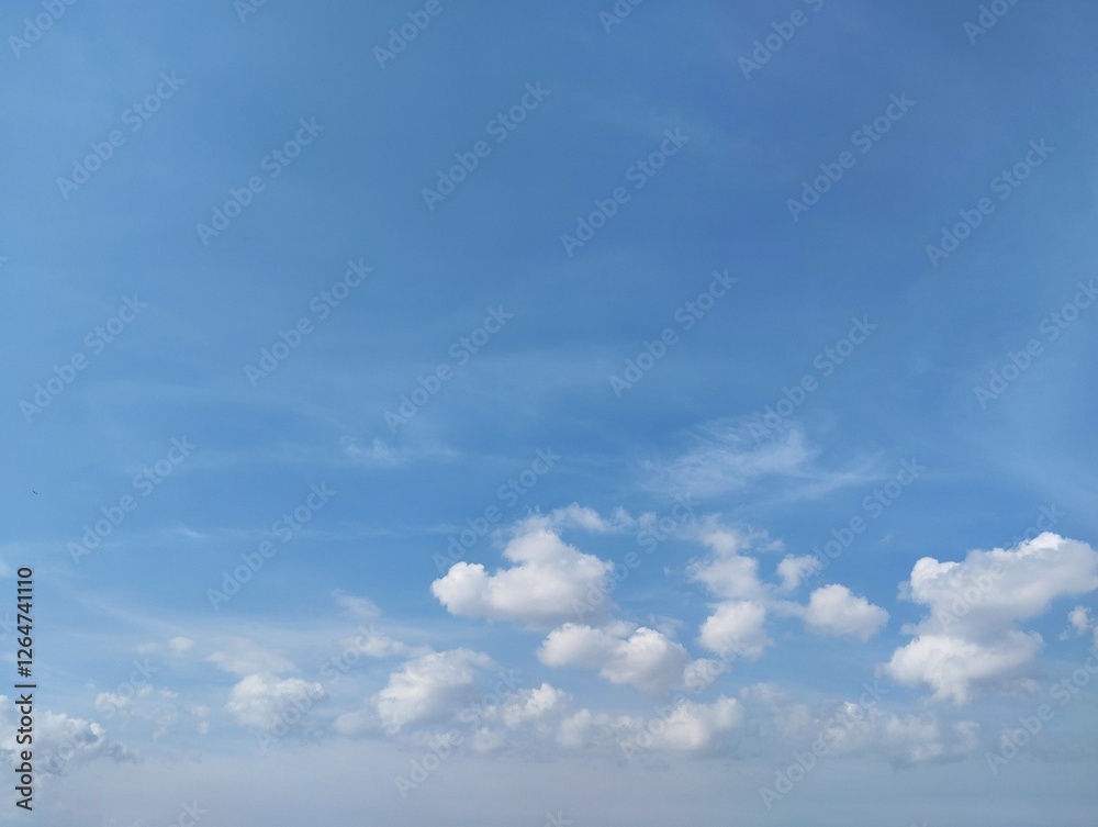 Clear blue sky with a few clouds. The sky is very bright and the clouds are scattered throughout. Natural background texture Clear blue sky with a few clouds. The sky is very bright and the clouds are scattered throughout. Natural background texture