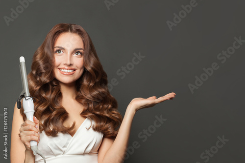 Fotografie Gorgeous woman with healthy long wavy hair  holding empty palm hand and using cu