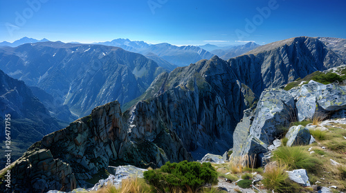 Mountain majesty: A breathtaking view of rugged mountain range stretching under a clear blue sky.