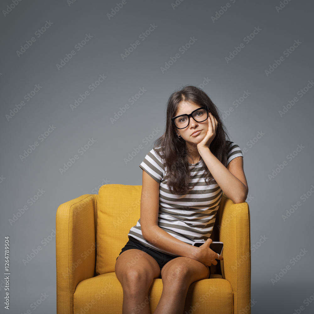 Obraz premium Portrait of a bored girl holding her smartphone