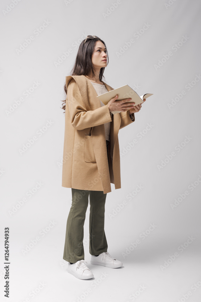 Attractive young woman holding a booklet and looking around Attractive young woman holding a booklet and looking around